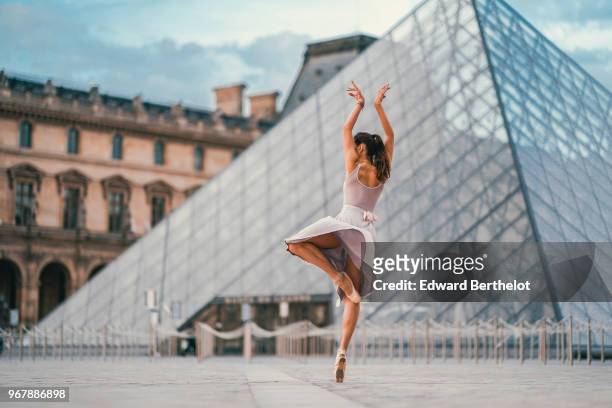 Ballet dancer Amanda Derhy performs a "Pirouette", wears a white leotard, repetto ballerina shoes and a light purple skirt, in front of the Louvre...
