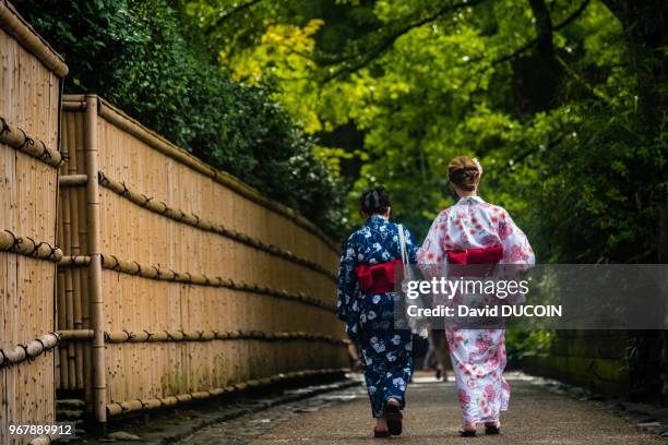 Japanese women in kimono in the bamboo forest in Sagano, Arashiyama area in Kyoto, Japan.