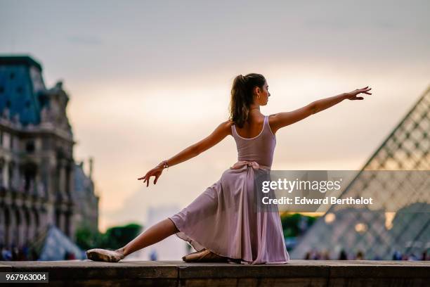 Ballet dancer Amanda Derhy, wears a white leotard, repetto ballerina shoes and a light purple skirt, in front of the Louvre, on May 27, 2018 in...