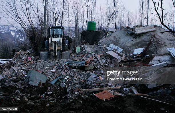 Bulldozer clears the remains of a house as Indian army soldiers search for dead bodies of militants after a gun battle on February 17, 2010 in Kachwa...