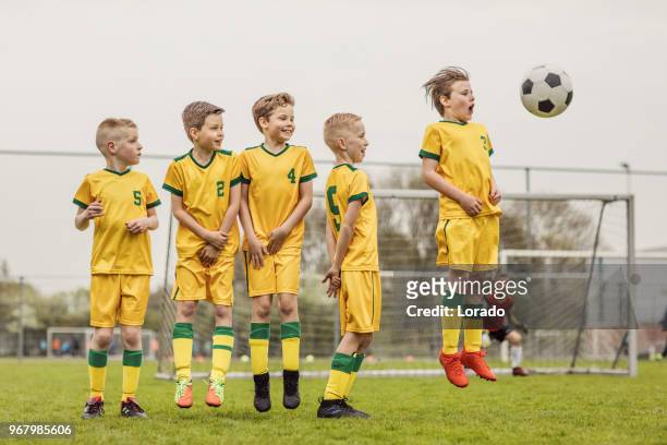 een jongens voetbal team de oprichting van een defensieve muur tijdens een voetbalwedstrijd - verdediger voetballer stockfoto's en -beelden