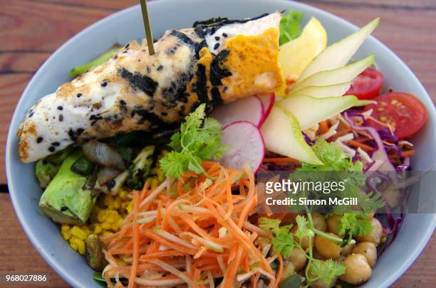 buddha bowl with salad, pear, cherry tomato, red cabbage, broccoli, charred greens, chickpeas, grated carrot, sprouts, rice, grains, nuts, seeds & lemon hummus topped with a seaweed & black sesame omelette - schwarzer sesamsamen stock-fotos und bilder