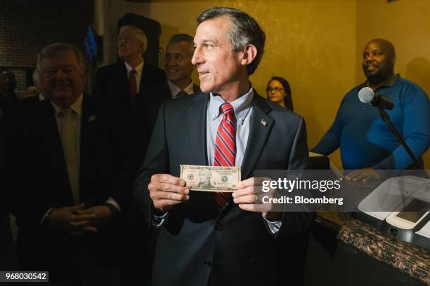 John Carney, governor of Delaware, holds a U.S. Ten dollar bank, symbolizing the ceremonial first bet, during the launch of full-scale sports betting...