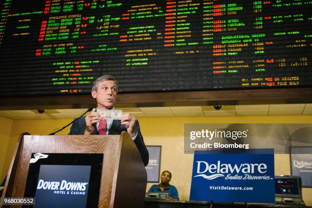 John Carney, governor of Delaware, holds a U.S. Ten dollar bank, symbolizing the ceremonial first bet, while speaking during the launch of full-scale...