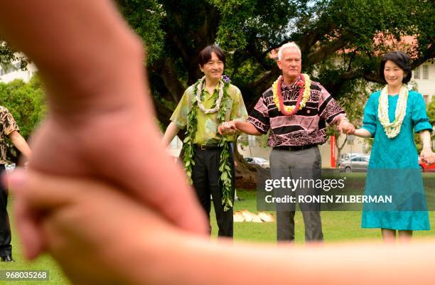 Prince Akishino of Japan, Honolulu Mayor Kirk Caldwell and Princess Kiko of Japan hold hands as they bless a tree after planting it at Thomas Square...