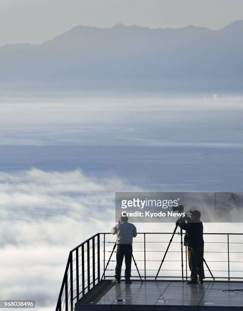 Photographers take pictures of a sea of clouds from an observatory deck on a mountain facing the Seto Inland Sea in the western Japan city of...