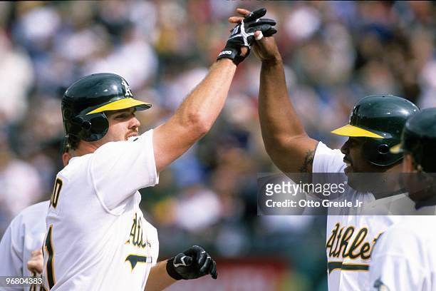 Scott Spiezio and Kevin Mitchell of the Oakland Athletics celebrate at home plate during an MLB game against the New York Yankees on April 4, 1998 at...