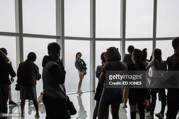 Visitors pose for photos as a viewing deck of the Lotte World Tower in Seoul on June 6, 2018. - French "Spiderman" Alain Robert, who holds a world...
