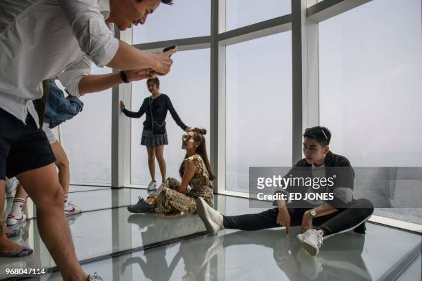 Visitors pose for photos as a viewing deck of the Lotte World Tower in Seoul on June 6, 2018. - French "Spiderman" Alain Robert, who holds a world...