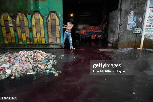 During a rainstorm color washes out of a dying factory in Shyampur, whose waste is dumped into the Buriganga river, on June 4, 2018 in Dhaka,...