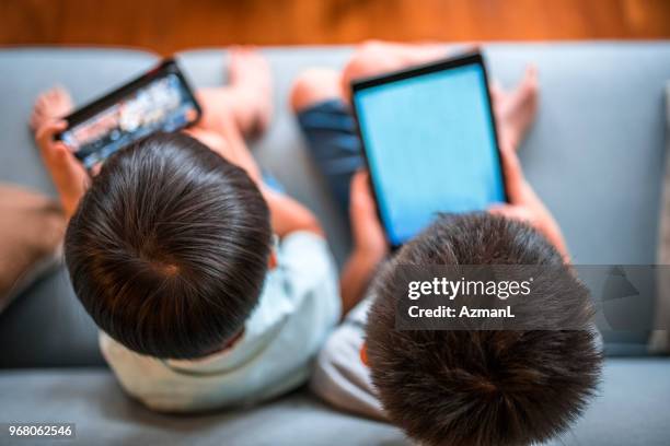 niños con tabla digital y sentado en un sofá - dispositivo de información móvil fotografías e imágenes de stock