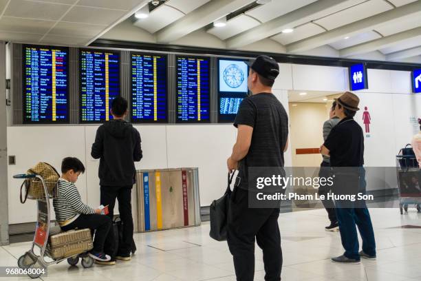 passengres searching for flight at the information board in hong kong international airport - le lounge stockfoto's en -beelden