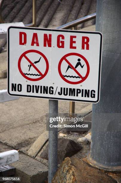 'danger: no swimming/jumping' sign near a jetty - kiama stock-fotos und bilder