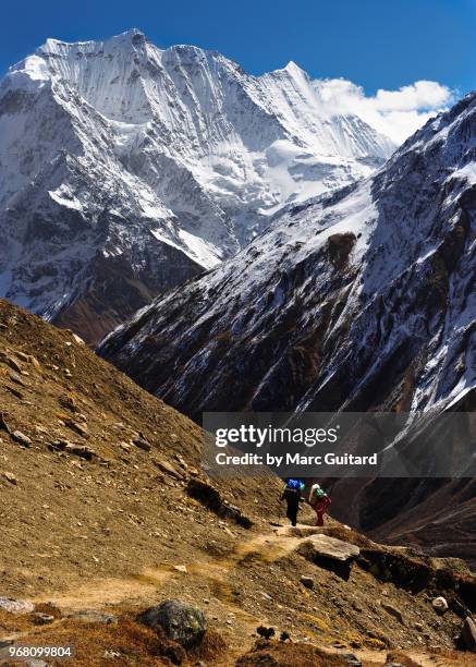two porters ascend a steep footpath on their way to dharamsala, manaslu circuit trek, nepal - dharamsala stock pictures, royalty-free photos & images