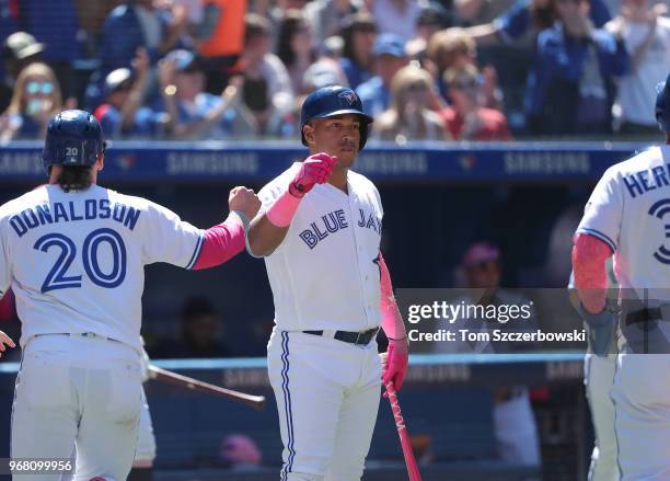 Josh Donaldson of the Toronto Blue Jays is congratulated by Yangervis Solarte after scoring on a two-run double by Justin Smoak in the fifth inning...