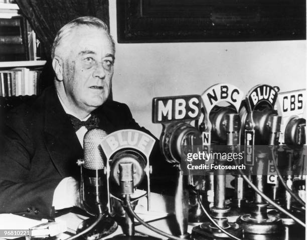 President Franklin D. Roosevelt seated in front of a number of television and radio station microphones, circa 1940s. .