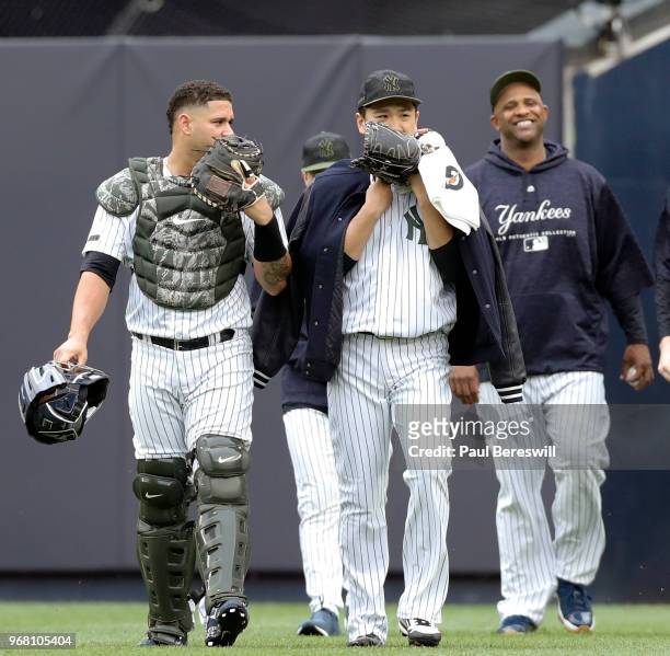 Catcher Gary Sanchez and pitcher Masahiro Tanaka of the New York Yankees walk in from the bullpen to start an MLB baseball game against the Los...