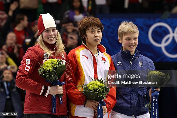 Marianne St-Gelais of Canada celebrates winning silver, Wang Meng of China gold and Arianna Fontana of Italy bronze during the flower ceremony for...