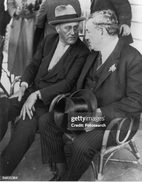 President Franklin D. Roosevelt seated speaking to a friend with crowd in background, circa 1940s. .