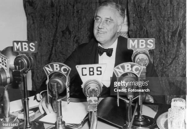 President Franklin D. Roosevelt seated in front of a number of television and radio station microphones in Washington D.C. Asking communities to...