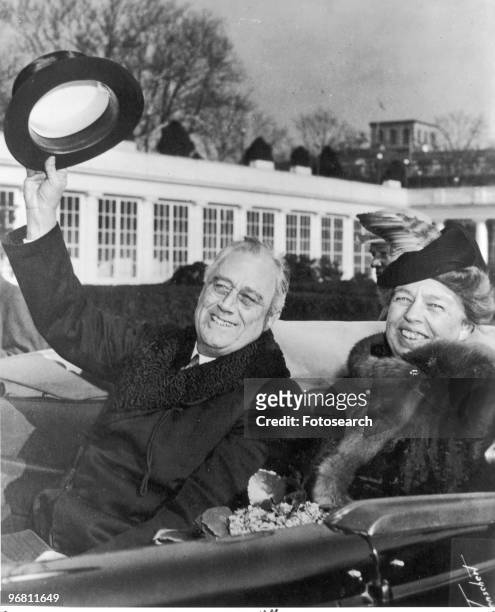 President Franklin D. Roosevelt and wife Eleanor Roosevelt smiling and waving from an open car returning from inauguration ceremonies, January 20,...