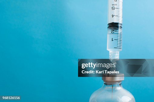 A syringe is injected into a vial A syringe is injected into a vial