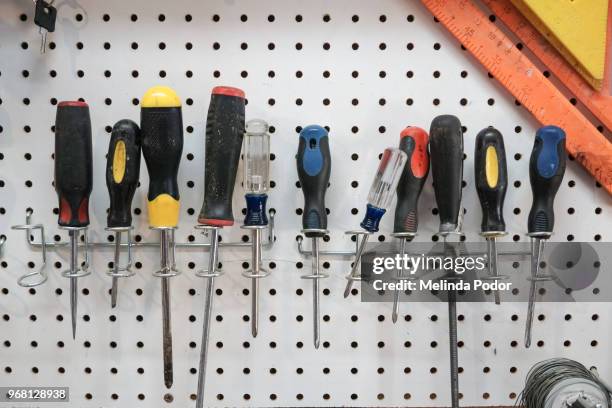 a collection of screwdrivers hanging from a pegboard - cacciavite foto e immagini stock