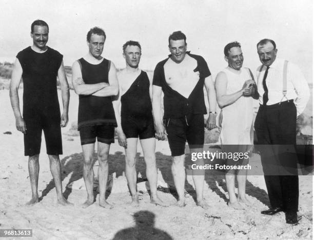 Portrait of President Franklin D. Roosevelt standing with friends and family on beach, circa 1920s. .