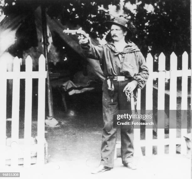 General Philip Sheridan stands outdoors aiming a pistol, circa 1870s. .