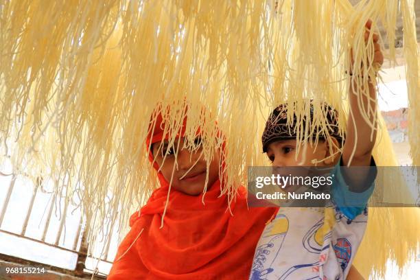 An Indian Muslim mansoori family's kids play around dries up traditional sweet dish 'Vermicelli' or 'Sewaiyan' for sale ahead the muslims festival...