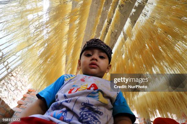 An Indian Muslim mansoori family's kids play around dries up traditional sweet dish 'Vermicelli' or 'Sewaiyan' for sale ahead the muslims festival...