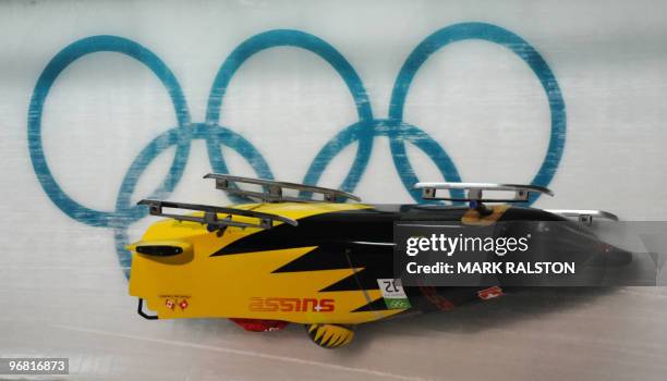 Members of the Switzerland 3 team led by pilot Daniel Schmid crash during the first training heat of the men's two-man bobsleigh event at the...