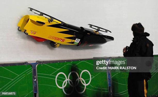 Members of the Switzerland 3 team led by pilot Daniel Schmid crash during the first training heat of the men's two-man bobsleigh event at the...