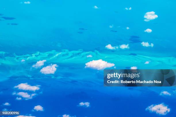 Beauty in nature in the Caribbean sea. Aerial view of the clouds and blue sea. Diverse blue tonalities. Point of view from an airplane arriving to...