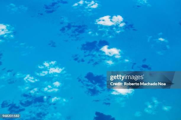 Beauty in nature in the Caribbean sea. Aerial view of the clouds and blue sea. Diverse blue tonalities. Point of view from an airplane arriving to...