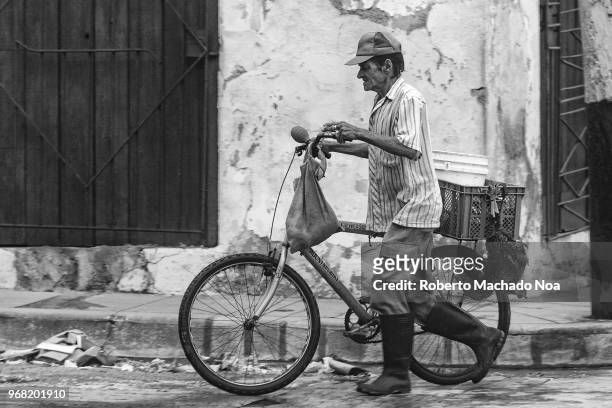 Cuban man with bicycle and carrying a live chicken possible for food. Everyday lifestyles in the Caribbean Island.
