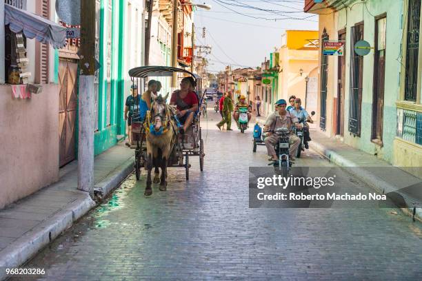 Horse drawn cart and motorcycles on city street. Transportation during daytime in the capital city of the province of Villa Clara.