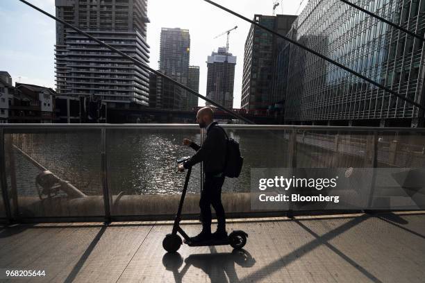 Man rides a scooter over a footbridge away from the Canary Wharf business, financial and shopping district in London, U.K., on Thursday, June 5,...