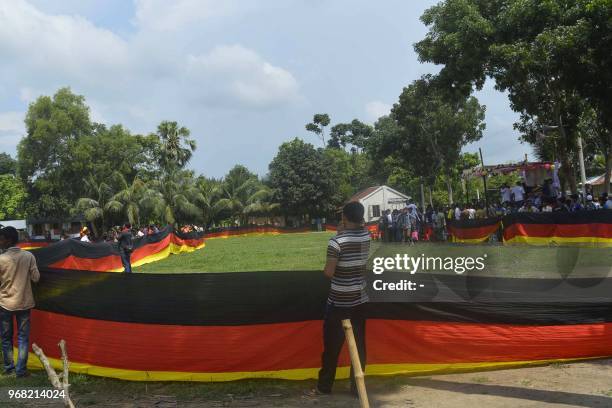 This photograph taken on June 5, 2018 shows Bangladeshi fans holding a large German flag displayed at a field in Magura. - A farmer in Bangladesh has...