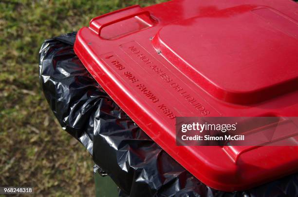 plastic wheelie garbage bin with a red lid on the grass verge of a suburban street - lid stock pictures, royalty-free photos & images