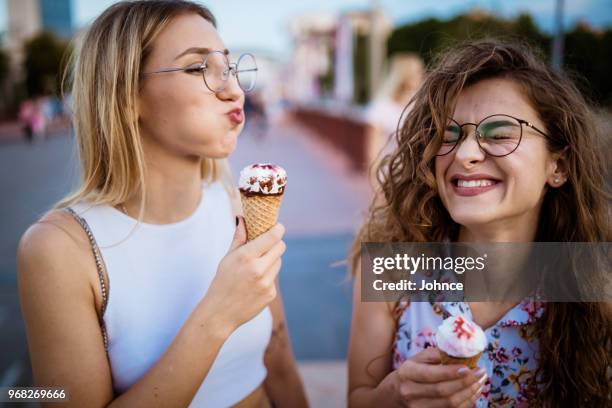美しい女性が徒歩でアイスクリームを食べる - 変な顔　女性 ストックフォトと画像