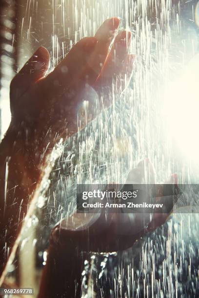 hands of woman in shower under the flowing water - arman zhenikeyev stock-fotos und bilder