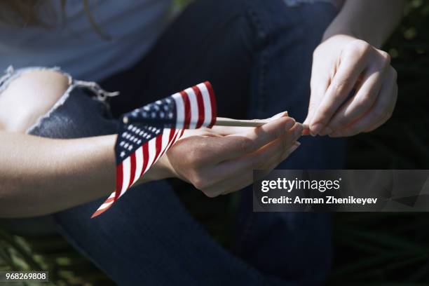 woman holding american flag - arman zhenikeyev stock-fotos und bilder