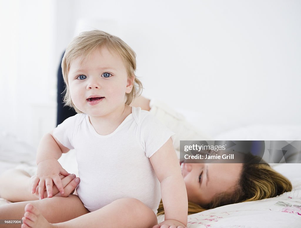 Mother and baby girl on bed