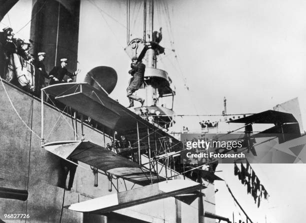 Photograph of a Glenn Curtiss and his Hydroplane being Hoisted above the USS Pennsylvania in San Diego Harbor circa 1911.
