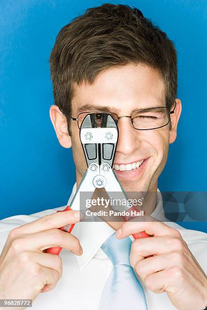 young man holding wire cutter over one eye - draadtang stockfoto's en -beelden