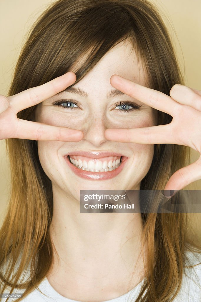 Young woman making peace signs and laughing