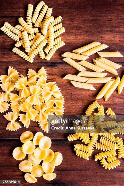 variety of types and shapes of dry italian pasta - fusilli, spaghetti, farfalle and penne, top view. uncooked whole wheat italian pasta. image with copy space. - bow tie pasta stock pictures, royalty-free photos & images