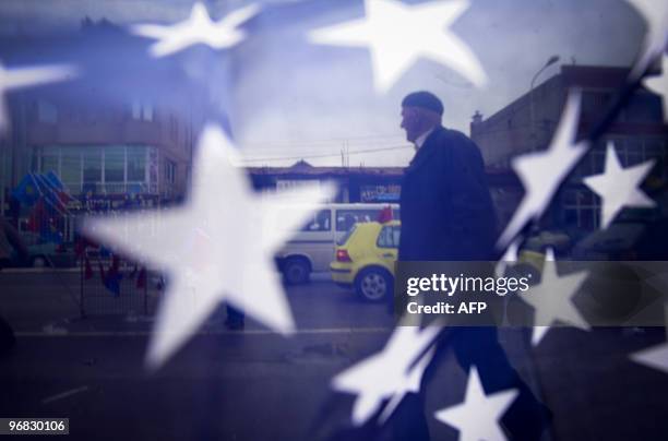 Kosovo Albanian man is seen through the US flag in the town of Mitrovica on February 17, 2010. Serbia will insist on fresh talks on the status of...