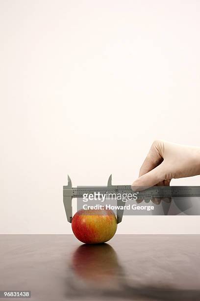 woman measuring width of apple - calipers stock-fotos und bilder